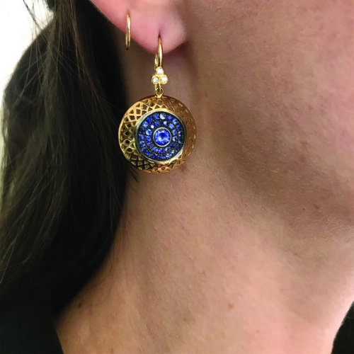 18k yellow gold crownwork disc earrings with blue sapphire center stones, 0.91 cttw, with pave-set blue sapphire surround, 2.10cttw, set in oxidized silver on triple diamond hooks. Earrings are 1 1/2" long x 7/8" wide (38 x 23mm).